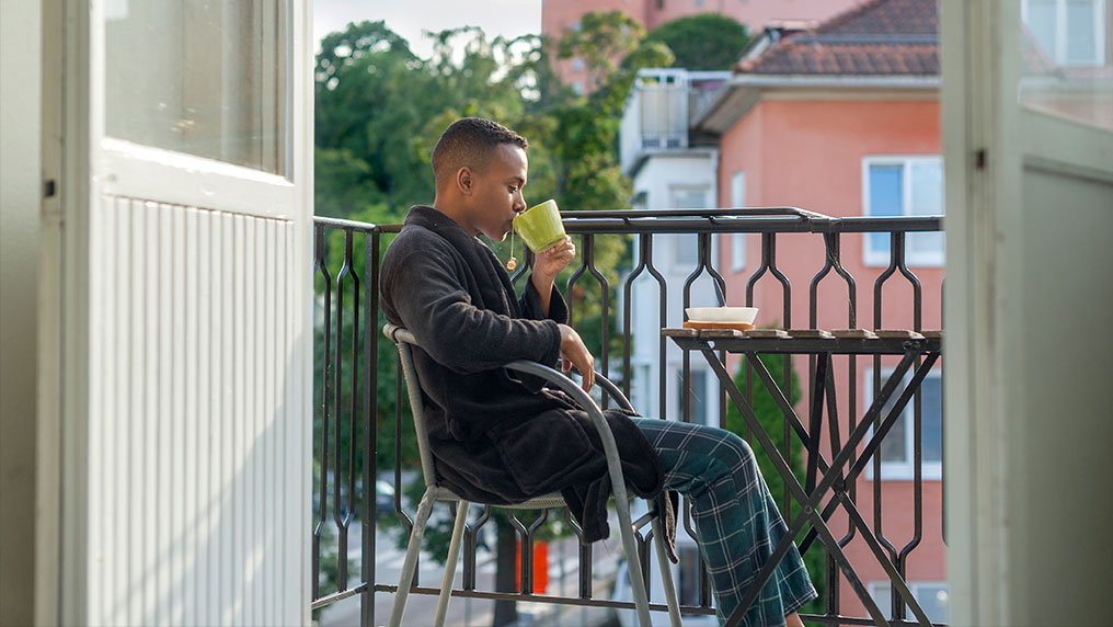 Student sitting on balcony with a cup of tea.