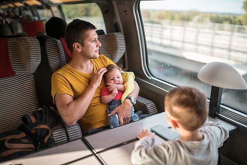 Man som reser med tåg tillsammans med två barn. 