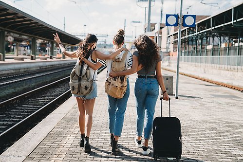 Three women walking along a train platform.