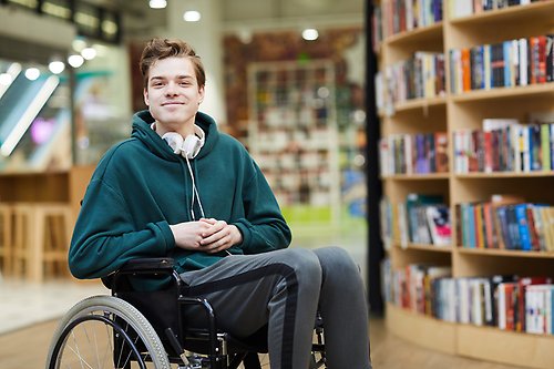 A person sitting in a wheelchair in a library.
