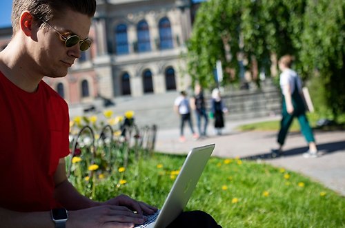 Student som jobbar ute framför en laptop.