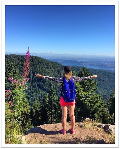 Student on top of a mountain with her arms open.